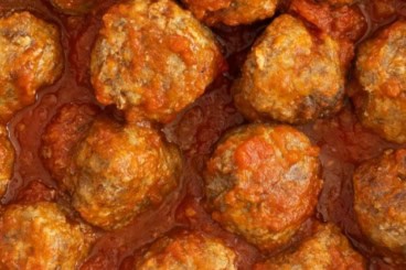 Sausage meatballs with sauce in pan.