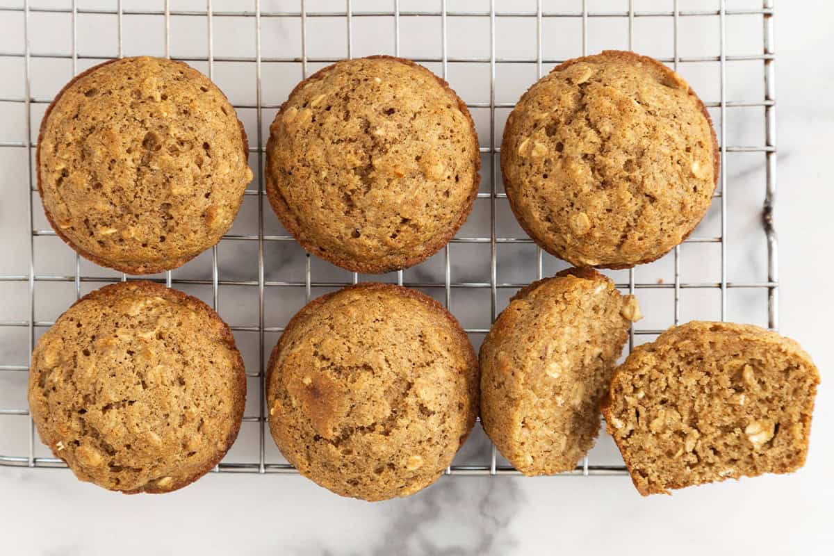 Oatmeal muffins on cooling rack with one cut open.