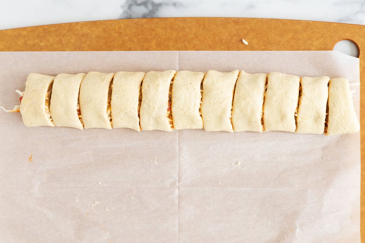slicing pinwheels into 1-inch pieces on parchment paper.