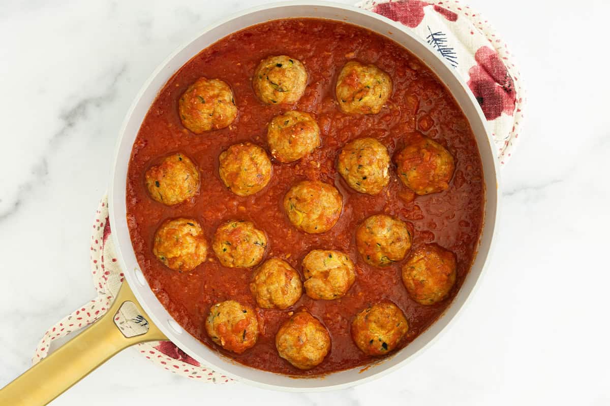 Turkey meatballs with zucchini in pan with tomato sauce.