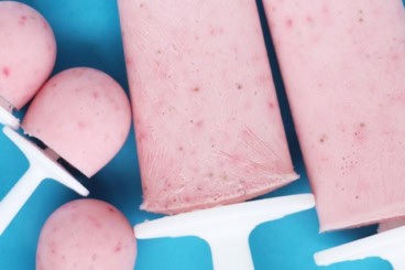 Strawberry popsicles on blue plate.