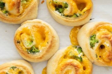 Broccoli cheese pinwheels on baking sheet.