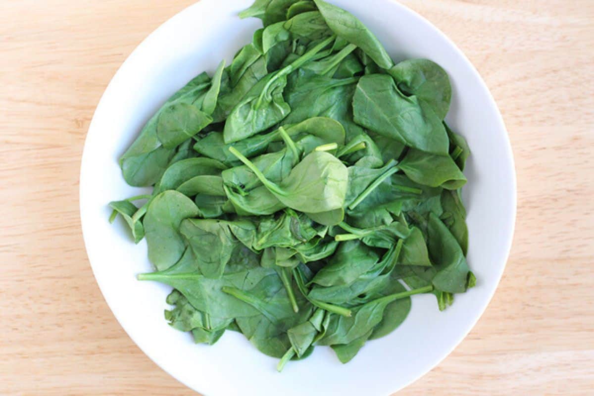 Spinach in white bowl for spinach quesadillas. 
