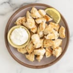 Chicken bites on grey plate with dipping sauce.