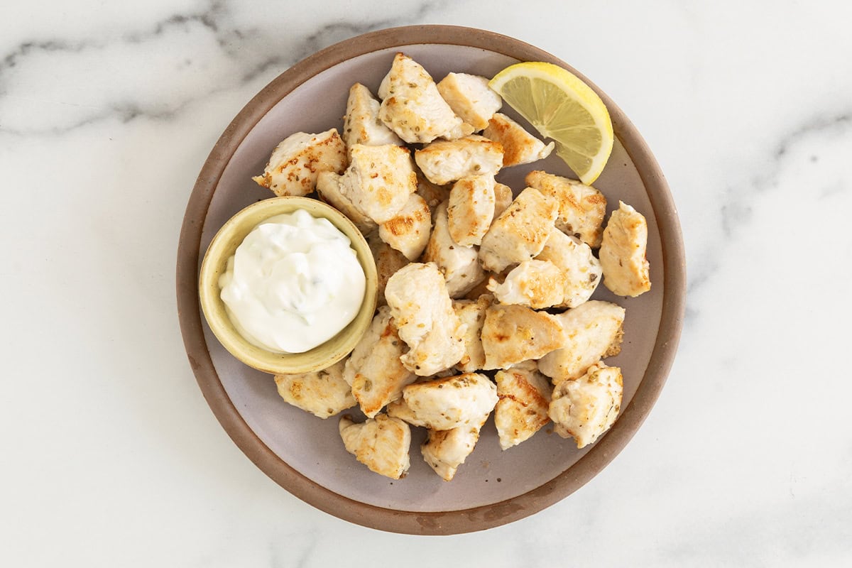 Chicken bites on grey plate with dipping sauce.