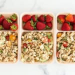 Farro salad in three lunch containers with strawberries.