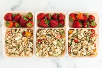 Farro salad in three lunch containers with strawberries.