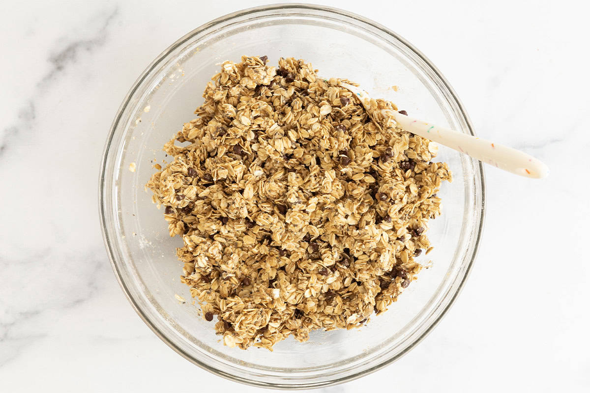 Mixture for healthy granola bars in glass bowl with spoon.