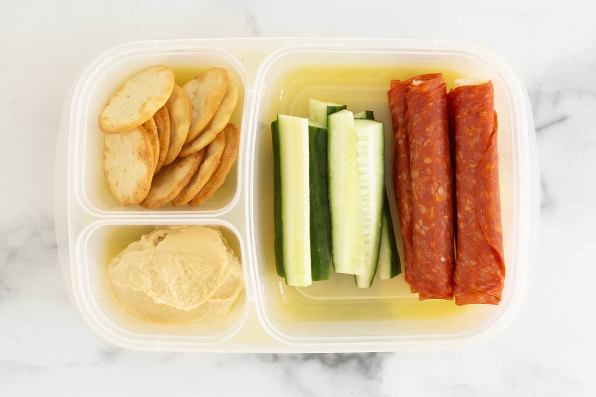 Lunchbox with salami, cucumber and crackers.