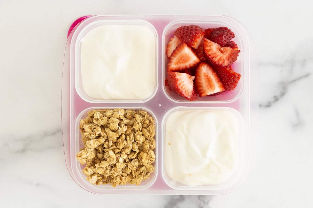 Lunchbox with yogurt, strawberries and granola.