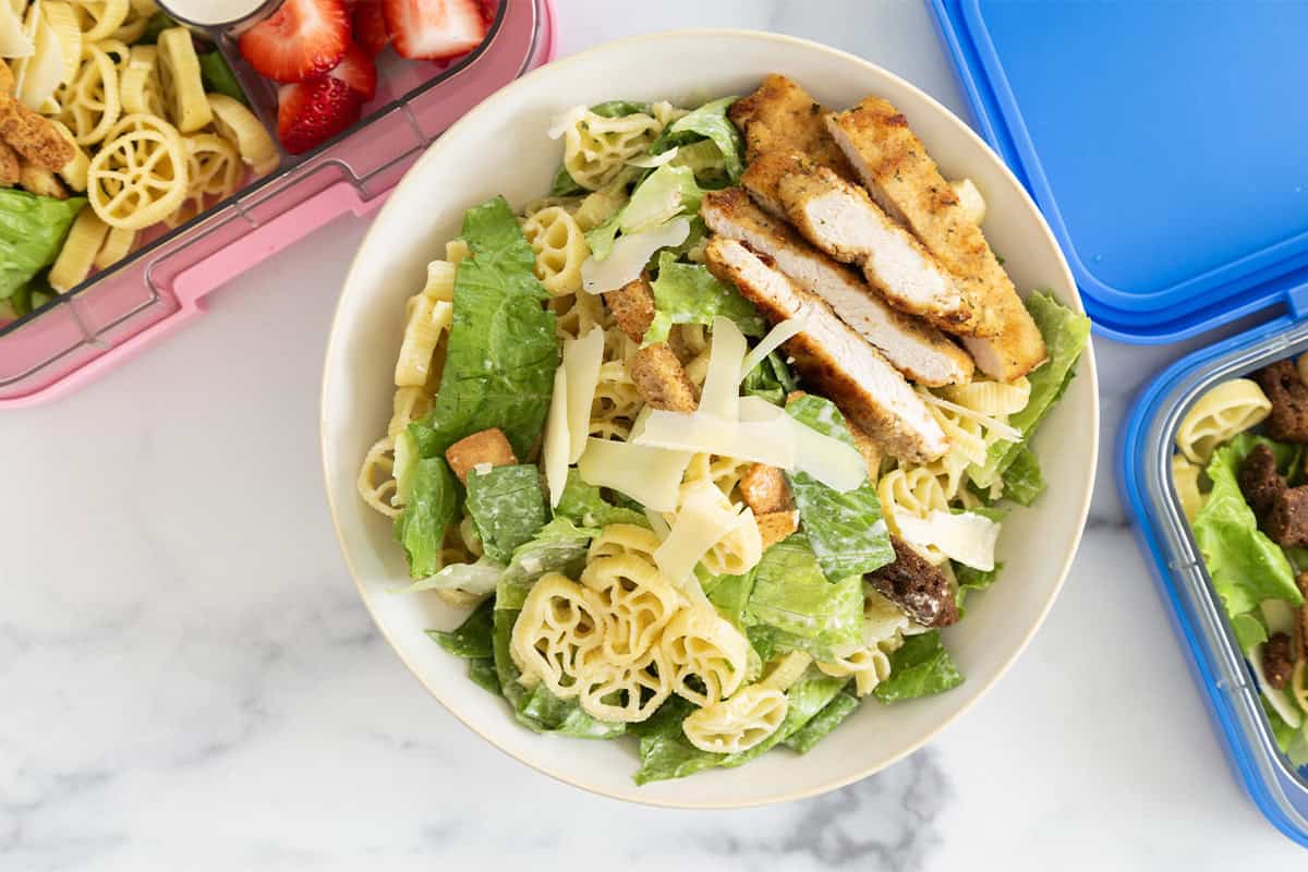 chicken caesar pasta salad in bowl and lunch boxes.