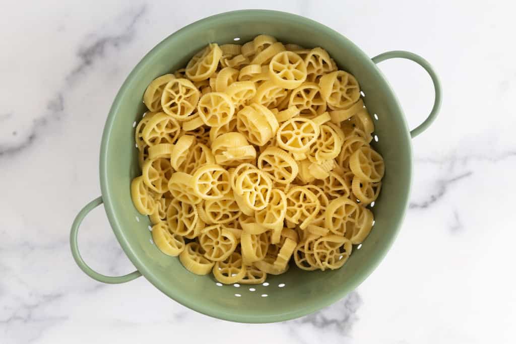 Pasta in strainer for chicken caesar pasta salad.