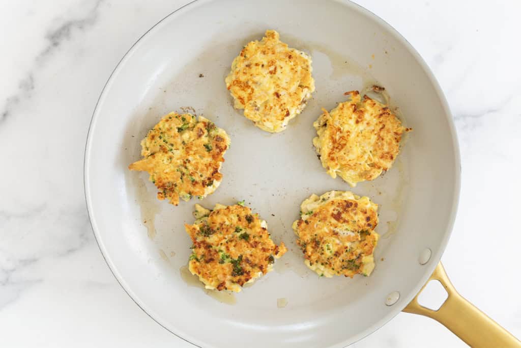 Chicken fritters in pan after flipping.