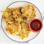 Chicken fritters on white plate with ketchup.