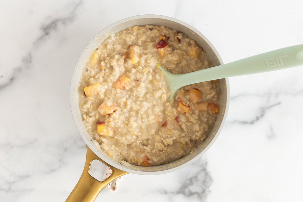 Peaches and cream oatmeal in pot with spoon.