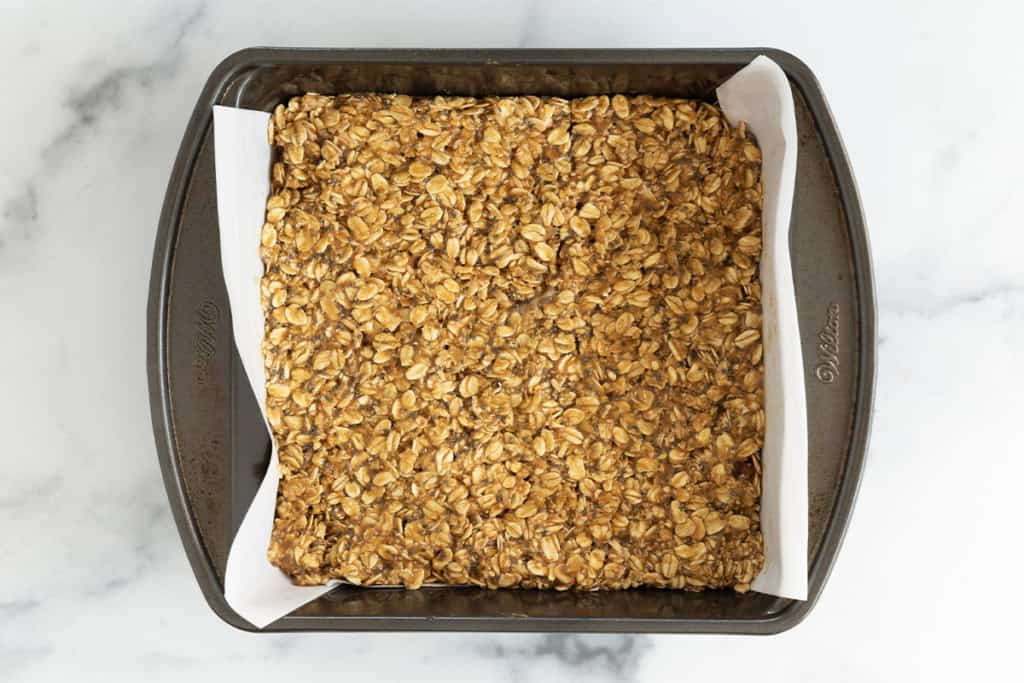 Peanut butter granola bars pressed into baking pan.