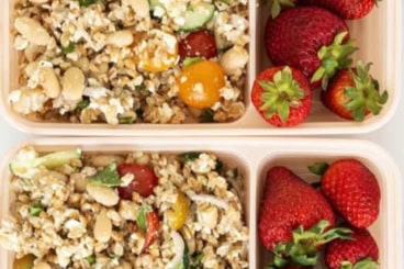 Farro salad in three lunch boxes with strawberries.