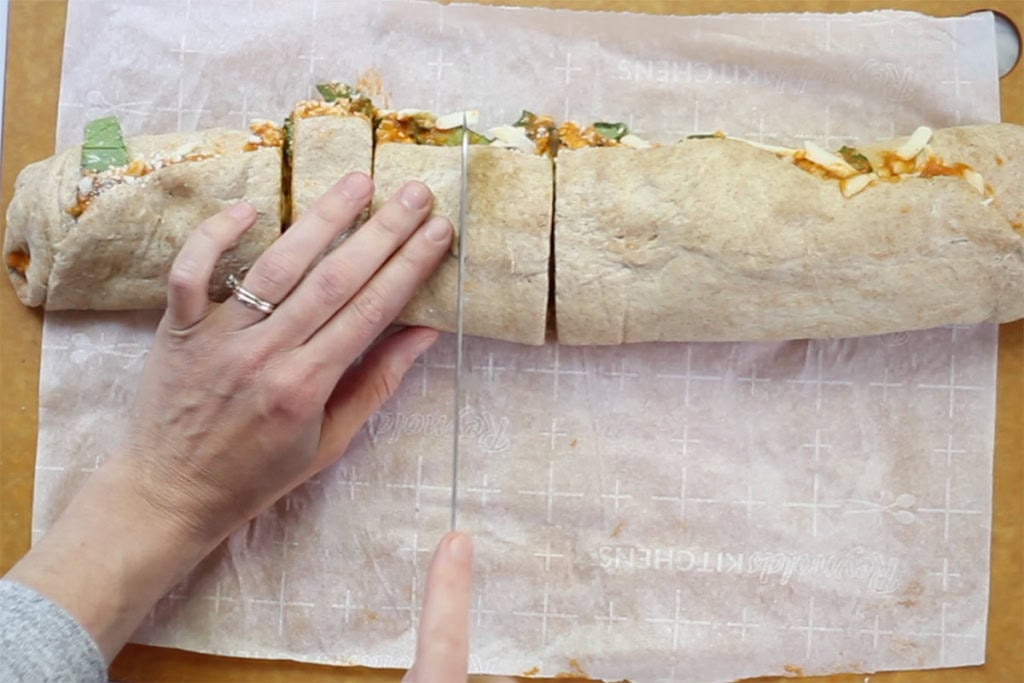 Cutting pizza rolls into slices to bake in oven.