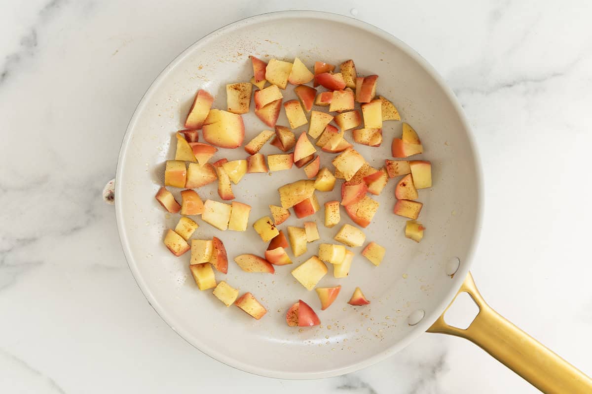 Apple pieces in frying pan for apple overnight oats.