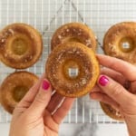 Hands holding baked donut.