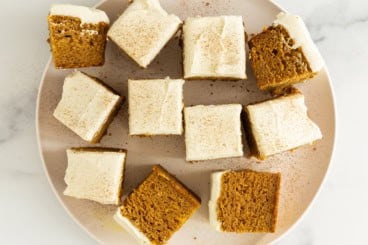 Squares of pumpkin cake on white plate.