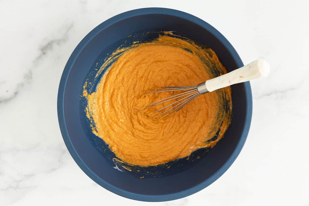 Batter for pumpkin cake in blue bowl with whisk.