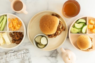 sloppy joes on three plates with sides.