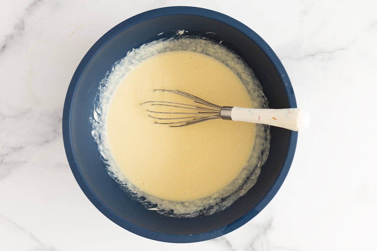 Wet ingredients in blue bowl for greek yogurt cake.