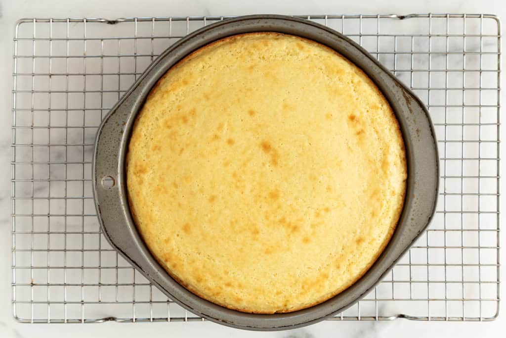 Greek yogurt cake in baking pan on cooling rack.