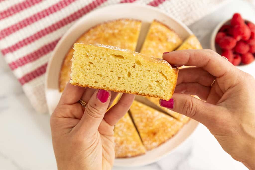 Hands holding slice of greek yogurt cake.