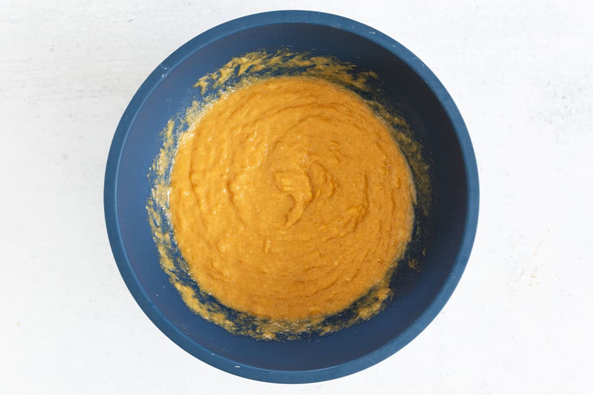 Wet ingredients for pumpkin banana bread in blue bowl.