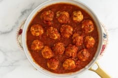 Ricotta meatballs in pan with tomato sauce.