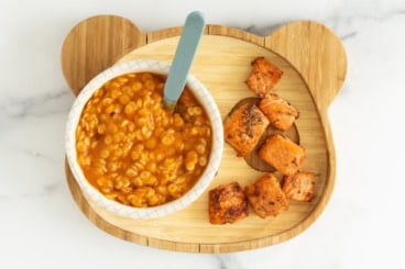 Salmon bites on plate with pasta on side.