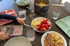 family dinner on table in bowls with child's arm.