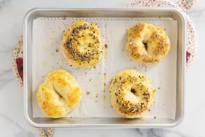 Four bagels on baking sheet after baking.