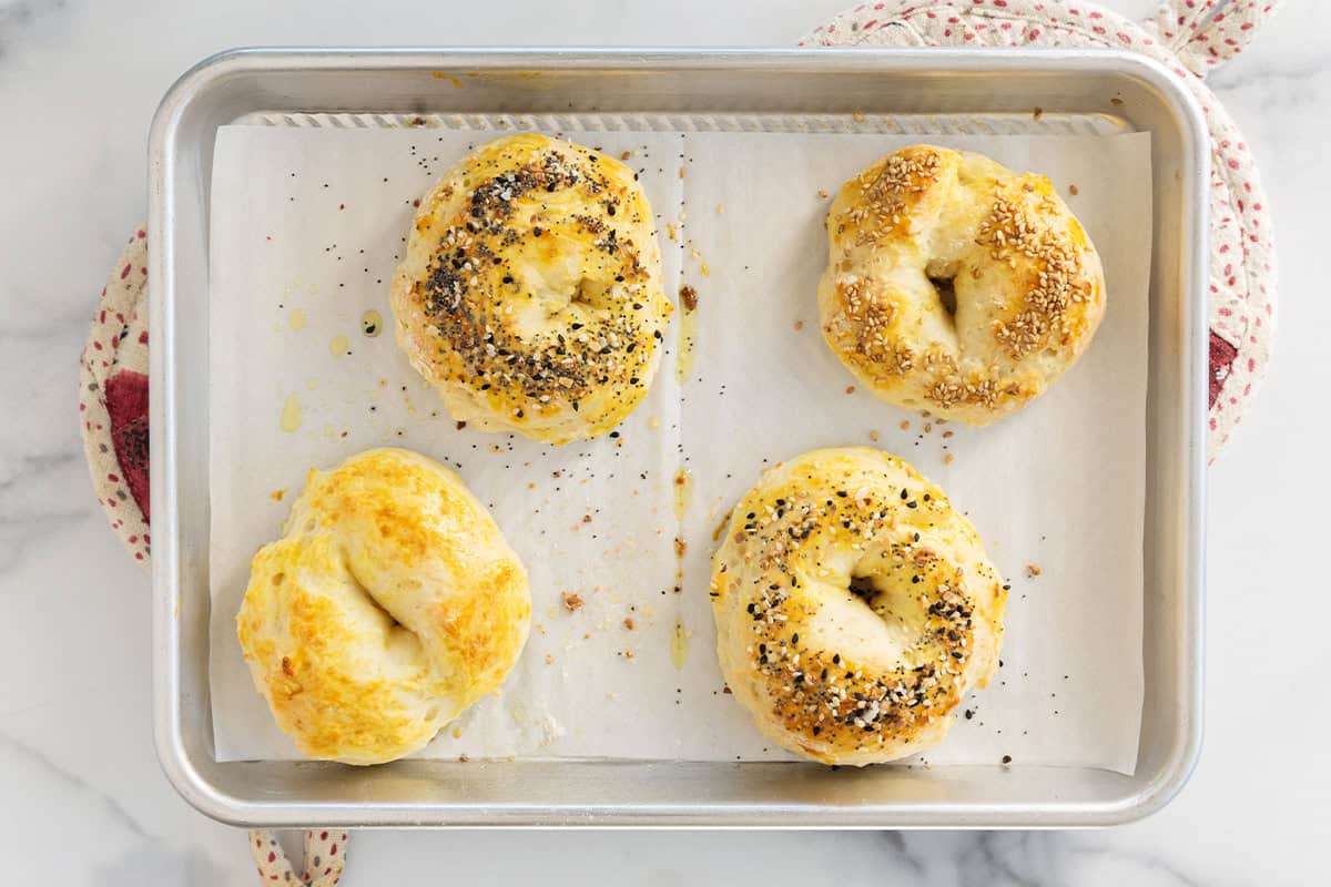 Four bagels on baking sheet after baking. 