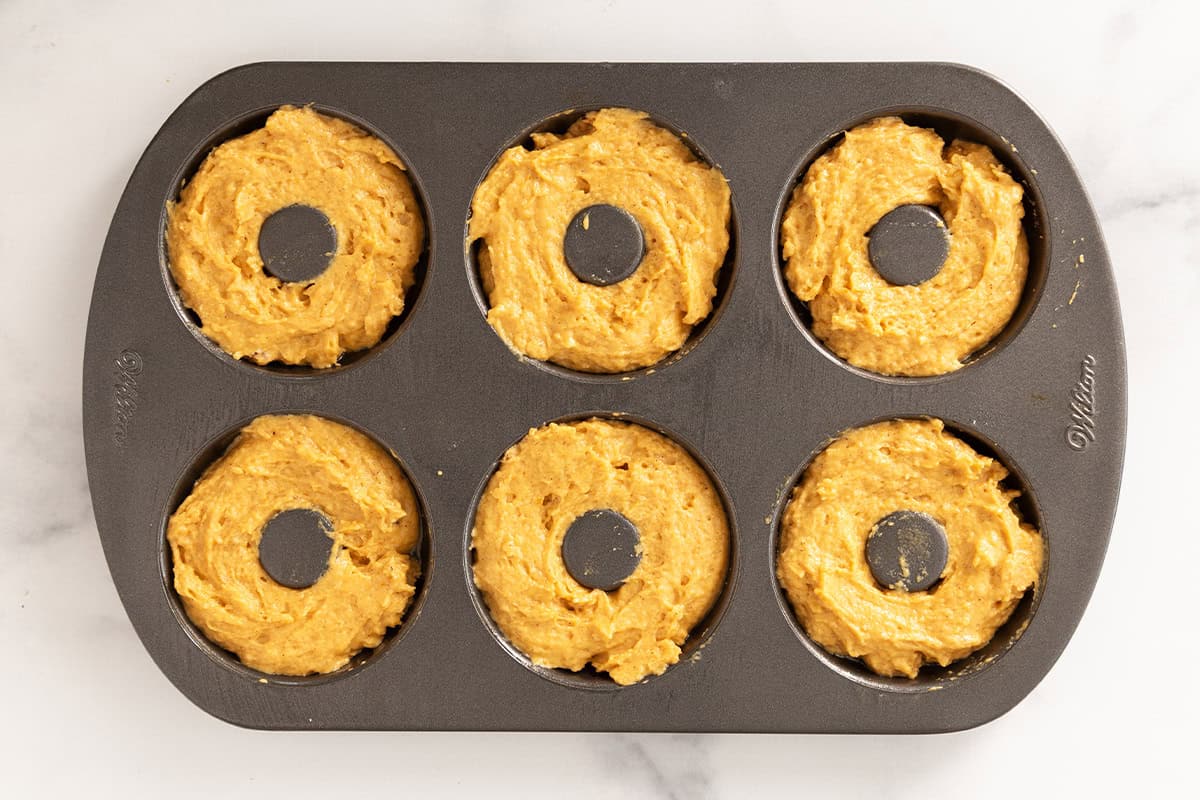 Pumpkin donuts in donut pan before baking.