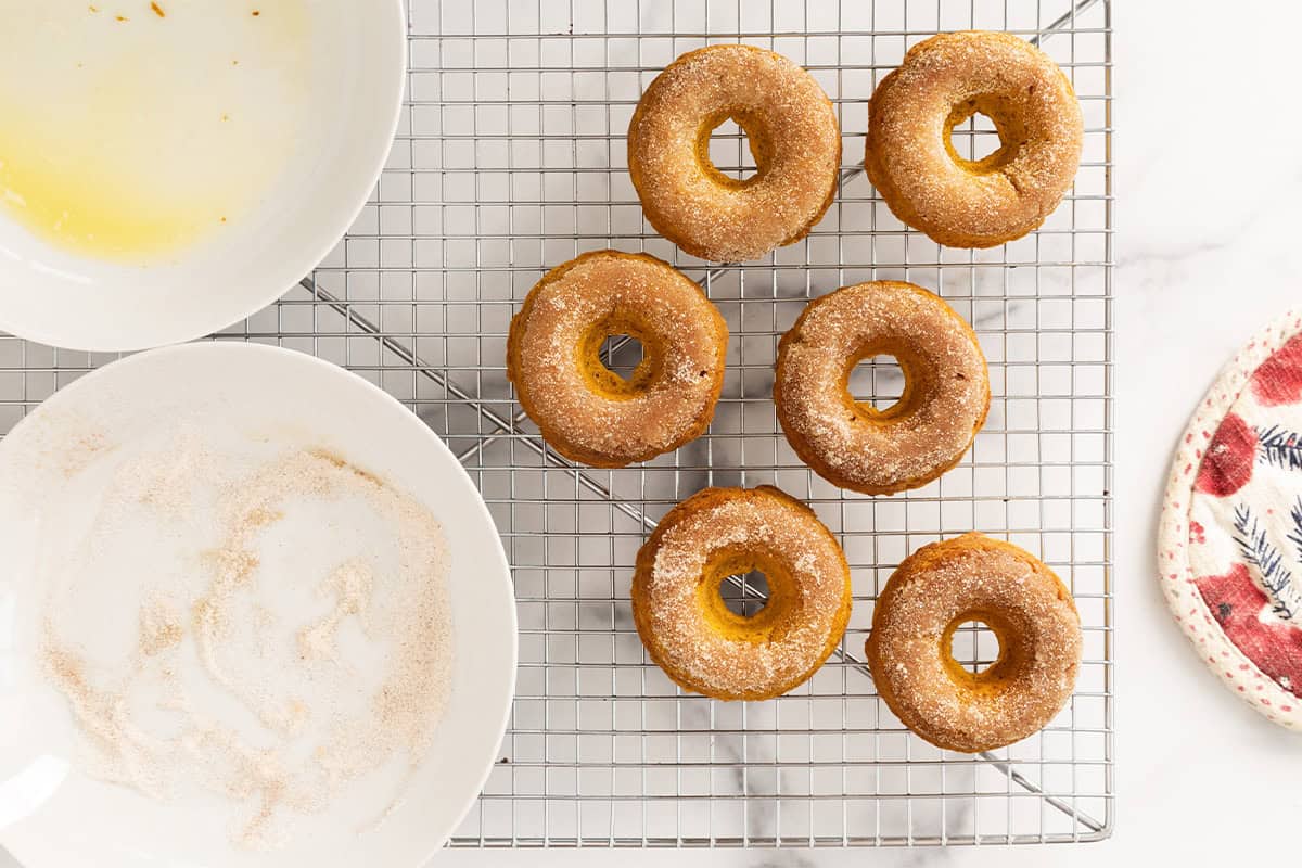 Pumpkin donuts with cinnamon sugar in bowls on side.