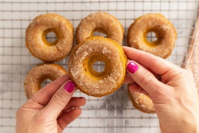 Hands holding pumpkin donut.