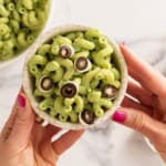 Hands holding bowl of halloween pasta.