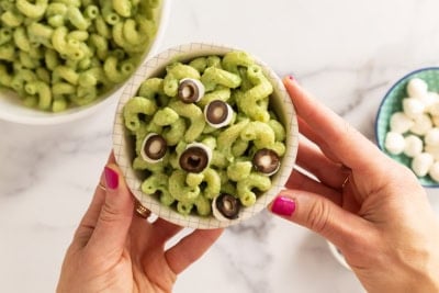 Hands holding bowl of halloween pasta.