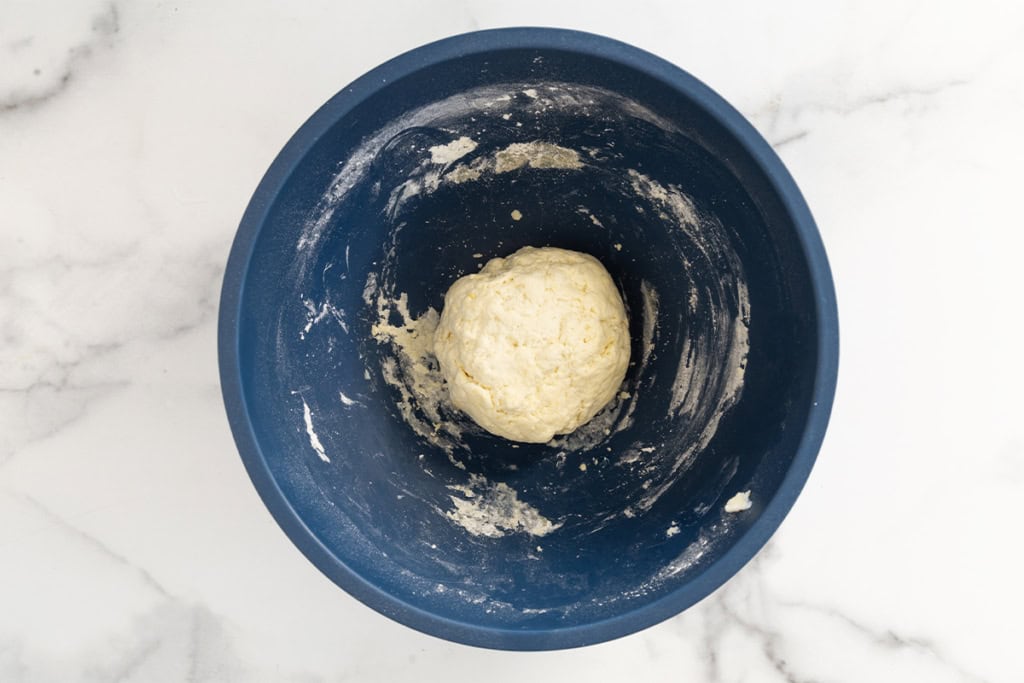 Dough for halloween pizza in blue bowl.