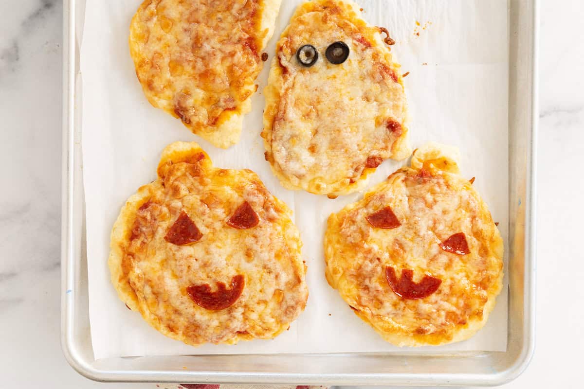 Halloween pizzas on baking sheet.