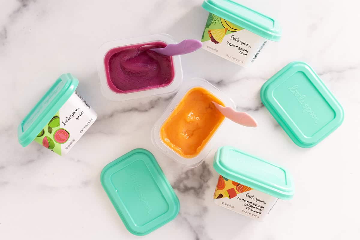 little spoon baby food in containers on counter top.