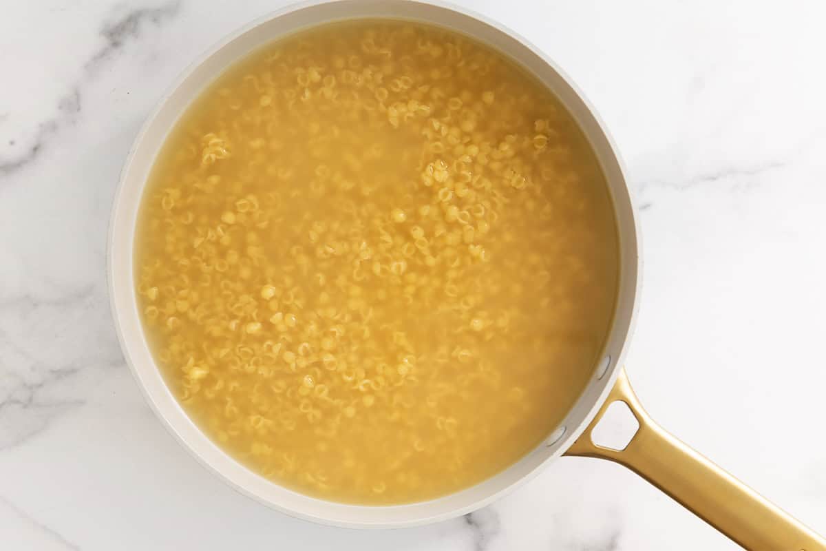 Broth with noodles in pan for one pot mac and cheese.