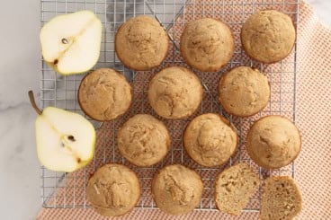 Pear muffins on cooling rack with pear halves on side.