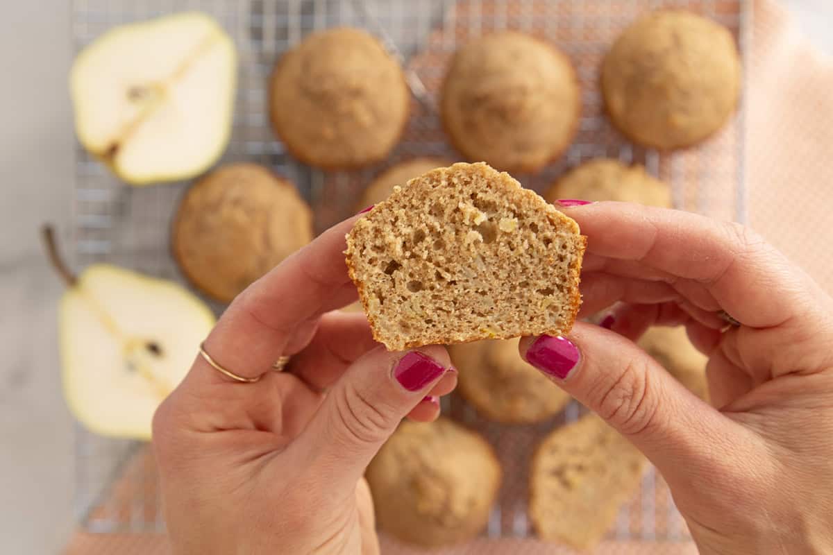 Hands holding half of a pear muffin.