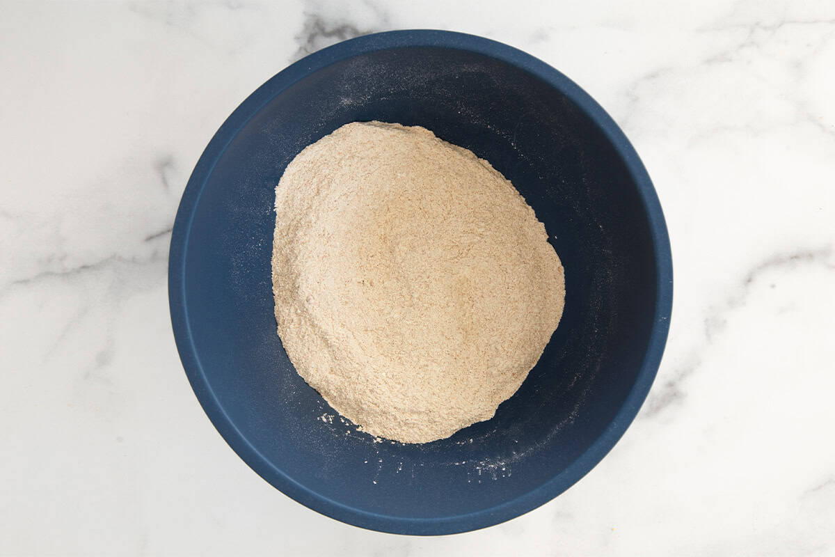 Dry ingredients for pear muffins in blue bowl.