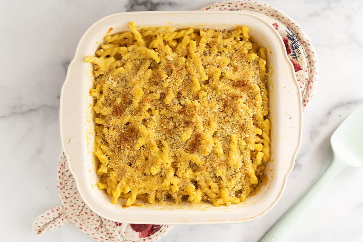 butternut squash pasta bake in baking dish on pot holders.