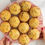 Christmas muffins on christmas plate with hands holding plate.